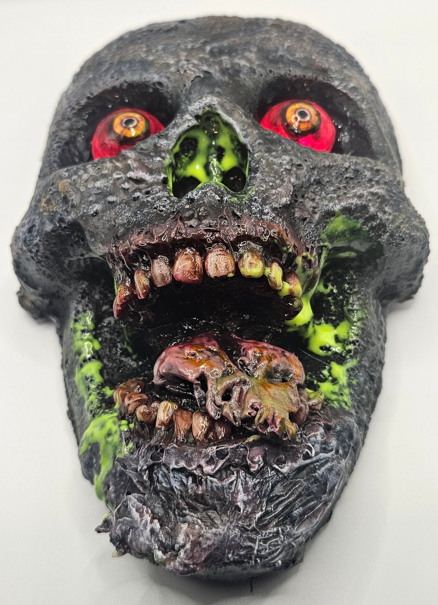 Decorative skull with glowing red eyes and greenish decay on a white background