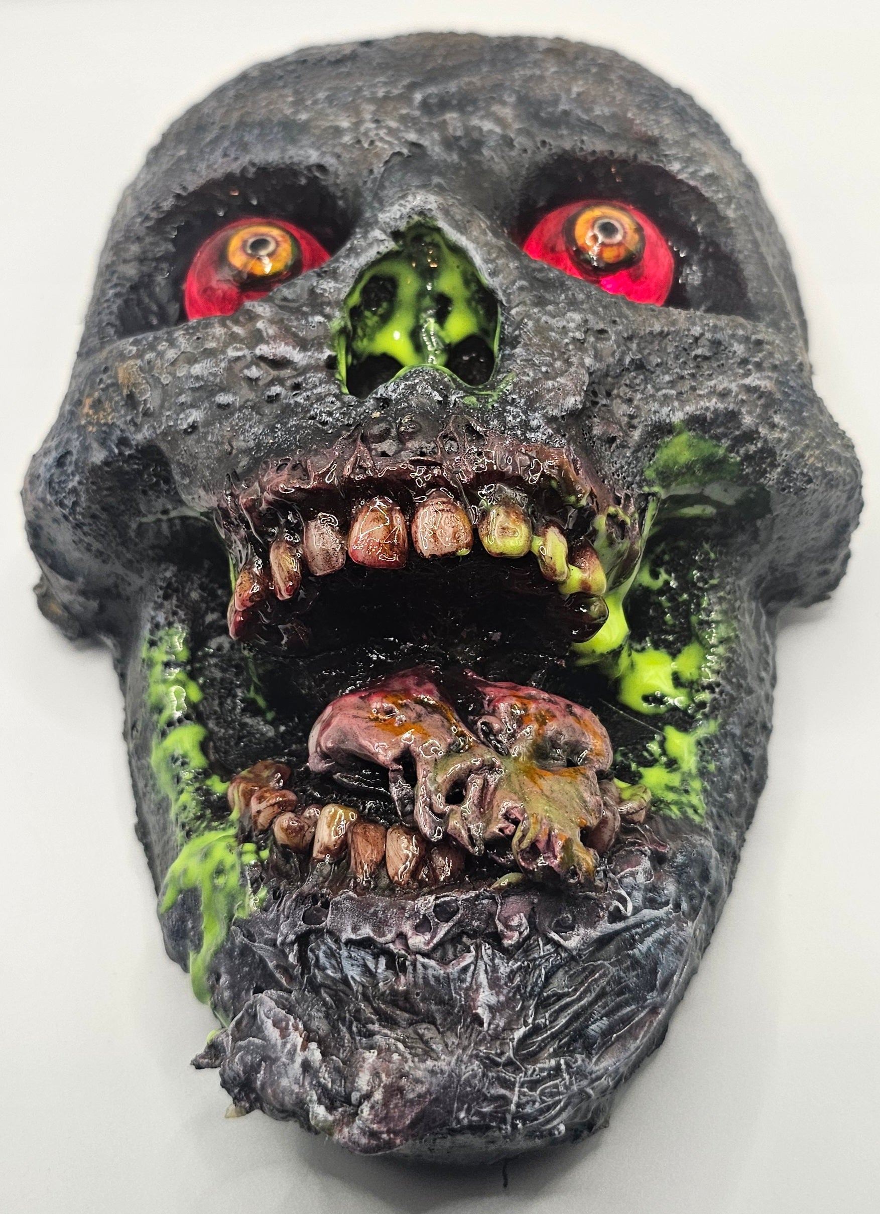 Decorative skull with glowing red eyes and greenish decay on a white background