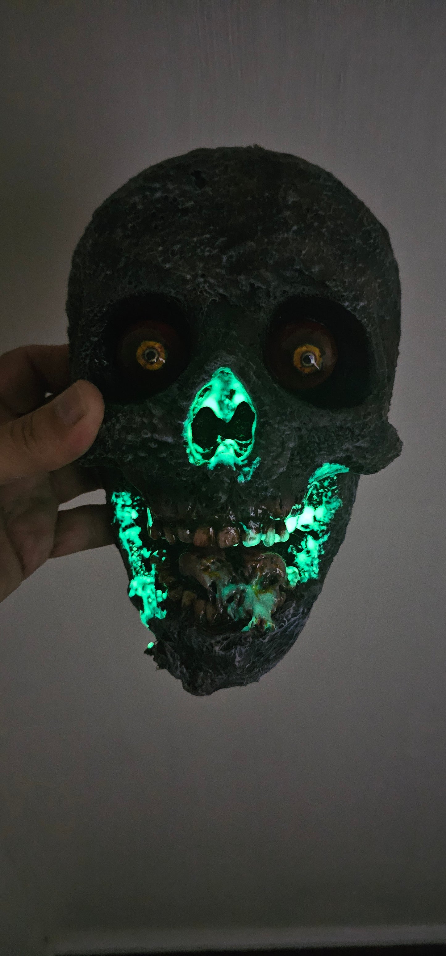 Glowing green stone held by a hand against a neutral background